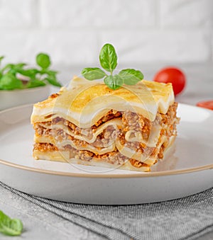 Slice of Lasagna bolognese with meat sauce and bechamel with melted cheese on top and fresh basil. Italian cusine. Copy space