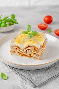 Slice of Lasagna bolognese with meat sauce and bechamel with melted cheese on top and fresh basil. Italian cusine. Copy space