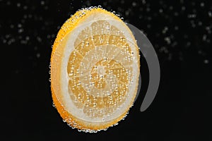 Slice of lemon in sparkling water on black background. Citrus soda