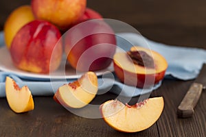 Slice of nectarine and whole fruits on a wooden table.