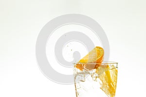 Slice the orange slice in a glass of water and make a spray on a white background. water spray in the air. a slice of citrus drops