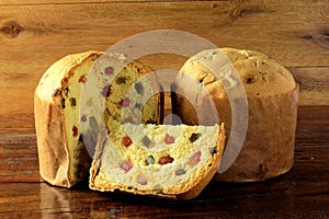 Slice of Panettone closeup with candied fruits wooden table. Christmas decoration.