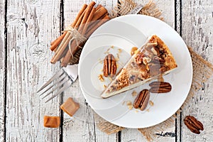 Slice of pecan caramel cheesecake, top view over white wood