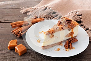 Slice of pecan caramel cheesecake on a wood background