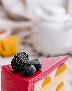 A slice of a pink strawberry cheesecake served with fresh berries on a white board