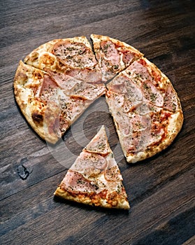 Slice of pizza with ham and cheese on wood table
