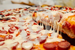 slice of pizza with a strech of  melted cheese, soft focus close up