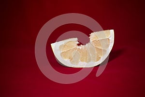 One slice of pomelo on a red table