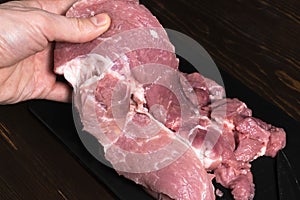 Slice the pork or beef with a knife on the table in close-up. Preparation of meat dishes and food products. Pieces of red meat for