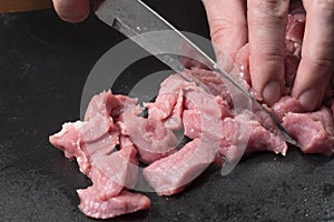 Slice the pork or beef with a knife on the table in close-up.Preparation of meat dishes and food products.Pieces of red meat for