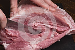 Slice the pork or beef with a knife on the table in close-up.Preparation of meat dishes and food products.Pieces of red meat for