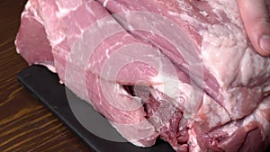 Slice the pork or beef with a knife on the table in close-up. Preparation of meat dishes and food products. Pieces of red meat for
