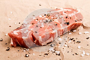 Slice of pork shoulder with coarse salt and crushed black pepper
