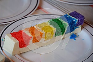 Slice of rainbow cake on top of a white plate