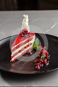 Slice of red velvet cake with raspberries on white plate on the table