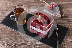 Slice of red velvet cake with white frosting is garnished with strawberries close up