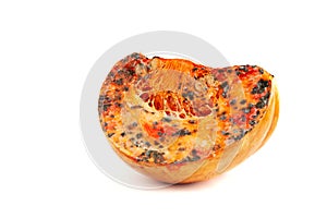 A slice of rotten orange pumpkin with mold on a white background