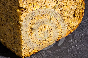 Slice of rustic natural yeast-free bread with flax, poppy seeds, sesame seeds, millet, pumpkin and sunflower seeds, on a