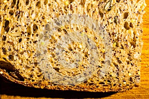 Slice of rustic natural yeast-free bread with flax, poppy seeds, sesame seeds, millet, pumpkin and sunflower seeds, on a