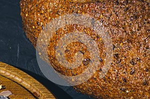 Slice of rustic natural yeast-free bread with flax, poppy seeds, sesame seeds, millet, pumpkin and sunflower seeds, on a