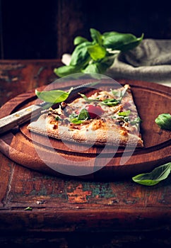 Slice of rustic pizza topped with fresh basil