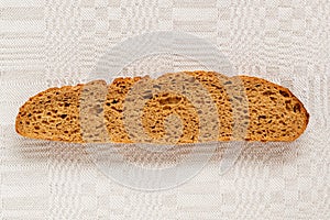 Slice of rye bread with an appetizing crispy brown crust on a gray linen tablecloth. Tasty, usefull and nutritious