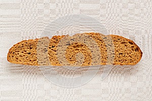 Slice of rye bread with an appetizing crispy brown crust on a gray linen tablecloth. Tasty, usefull and nutritious photo