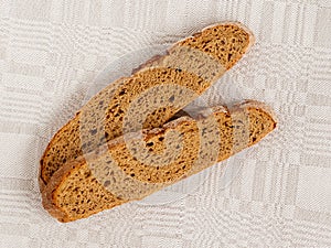Slice of rye bread with an appetizing crispy brown crust on a gray linen tablecloth. Tasty, usefull and nutritious. photo