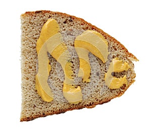 A slice of rye rural bread is smeared with yellow French mustard