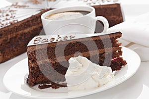 Slice of Sacher cake in plate with coffee