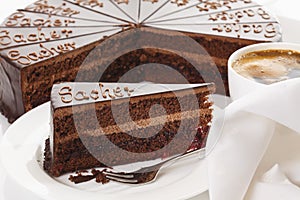 Slice of Sacher cake in plate with coffee