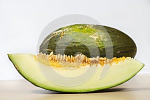 Slice of Santa Claus melon in front of the fruit