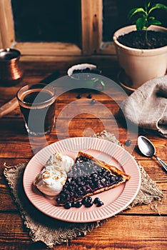 Slice of Serviceberry Pie and Two Scoops of Ice Cream on Plate with Glass of Coffee