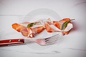 Slice of smoked ham on fork on a white background