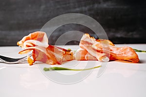 Slice of smoked ham on fork on a white background