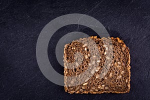 Slice of sunflower bread on black background