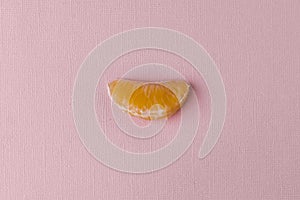 A slice of tangerine on a pink-pastel background.