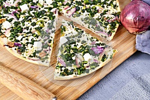 Slice of `Tarte Flambee` or `Flammkuchen`, a thin pizza-like baked pie from German-French Alsace border region, vegetarian