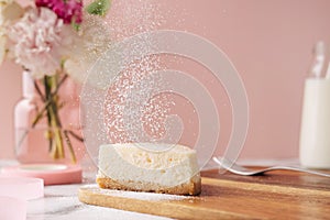 Slice of tasty homemade cheesecake with flowers and miilk on pink background. Healthy organic summer dessert pie.