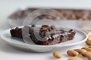 Slice of Texas sheet cake served on a plate. Buttery and chocolaty cake sliced to rectangular pieces inside the baking bin and