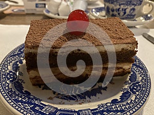 Slice of tiramisu cake for desset with a cherry on top