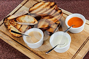 Slice of toast roasted in breaded with cheese and sesame slipped in a sauce on a wooden board