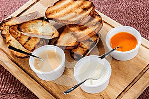 Slice of toast roasted in breaded with cheese and sesame slipped in a sauce on a wooden board