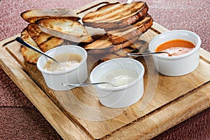 Slice of toast roasted in breaded with cheese and slipped in a sauce on a wooden board