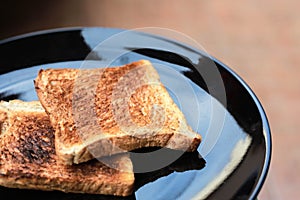 Slice toasted bread on black dish.