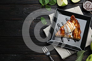 Slice of traditional apple pie with ice cream served on black wooden table, flat lay. Space for text