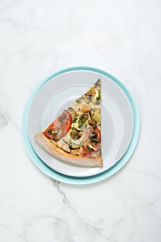 Slice of Vegan vegetable pizza. Dish with tomatoes, eggplant, champignons, Mozzarella cheese and basil pesto sauce.