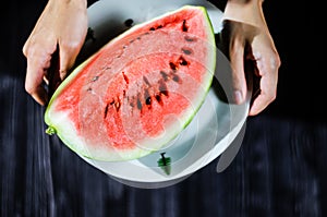 Slice of watermelon on white plate on hands photo