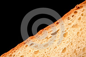 slice of white bread close up  on a black background. rough dappled textured surface chopped piece loaf of natural organic