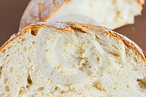 A slice of white fresh crispy bread on a brown background